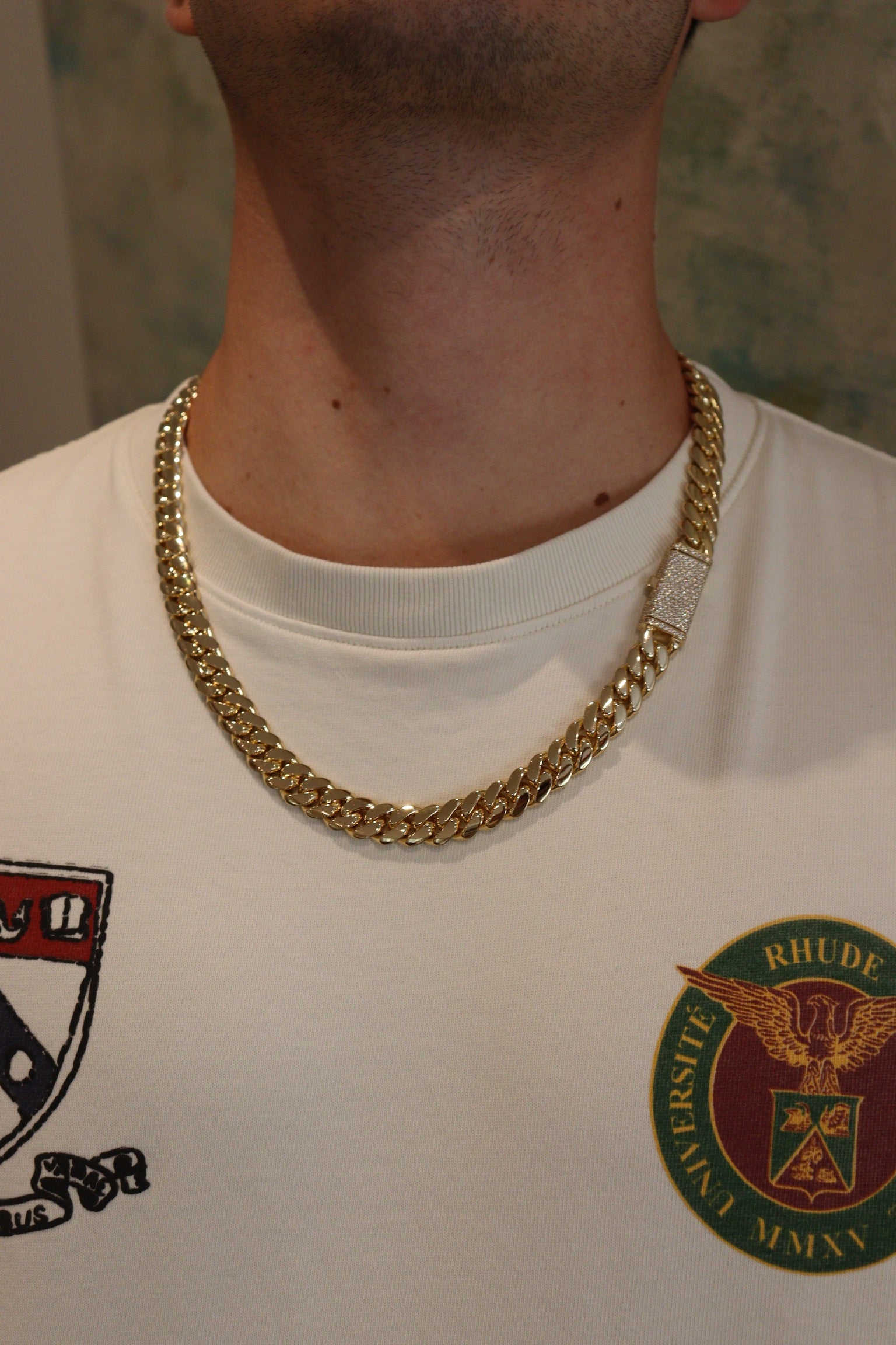 12MM Cuban Link Chain in yellow gold with fully iced-out VVS1 Moissanite Stones Lock, modeled on a 6’1” 180 lbs male wearing a white shirt. Jewelry by SF Jeweler 305.