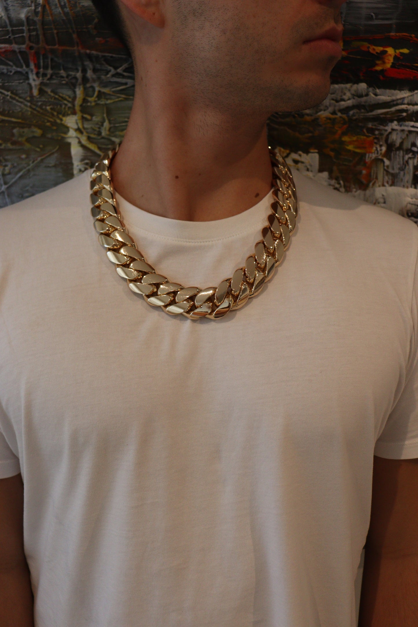 Man wearing a 28MM 26-inch yellow gold over silver Cuban link chain, modeled by SF Jeweler 305. The bold Miami Cuban chain has a heavy, polished finish and is styled with a casual t-shirt.