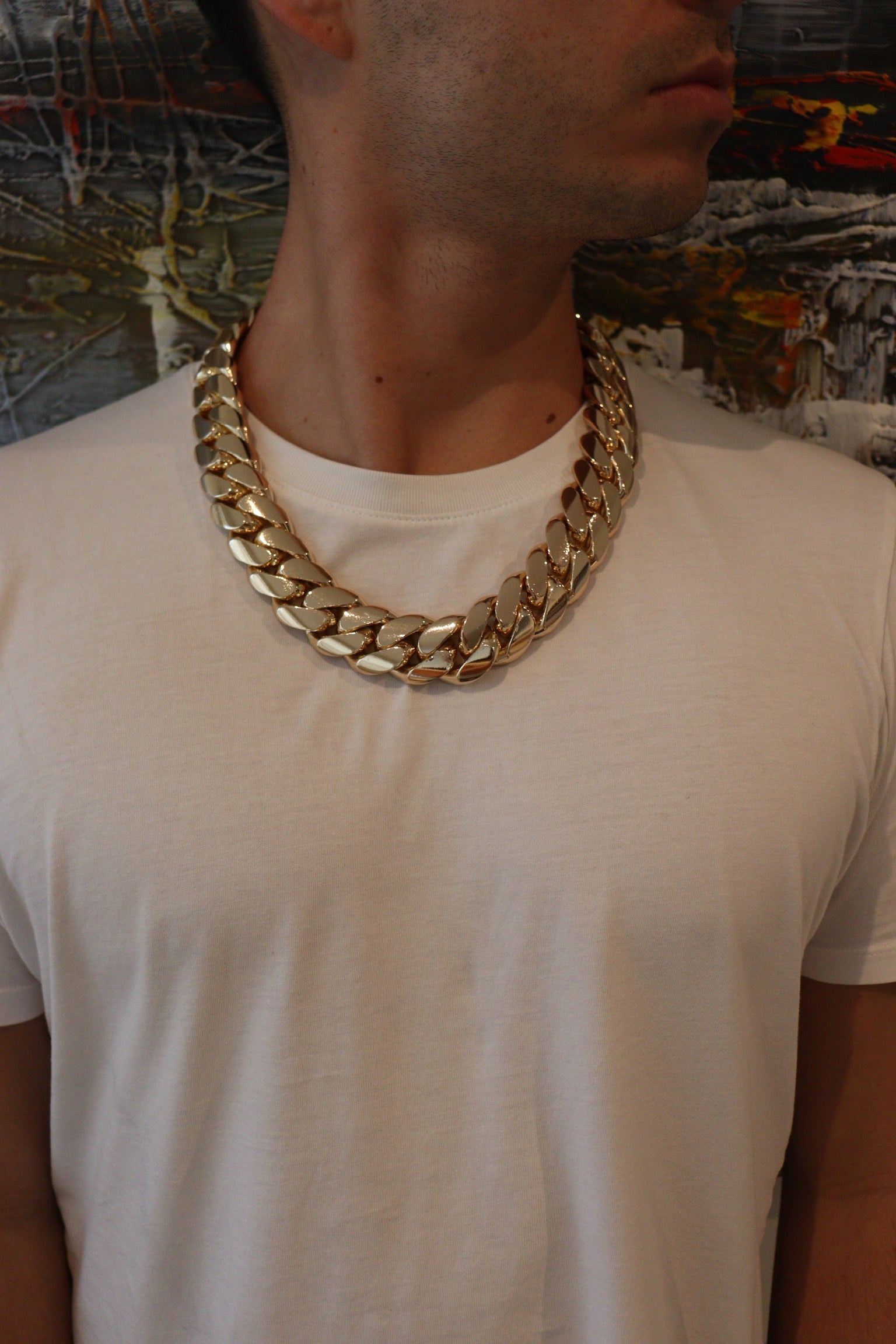 Man wearing a 28MM 26-inch yellow gold over silver Cuban link chain, modeled by SF Jeweler 305. The bold Miami Cuban chain has a heavy, polished finish and is styled with a casual t-shirt.
