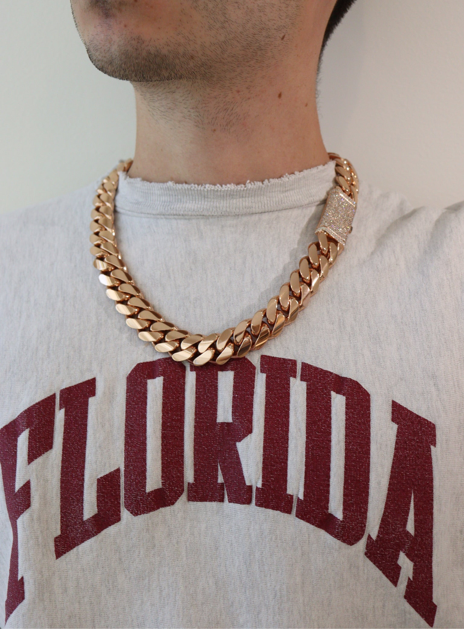 20MM Cuban Link Chain in rose gold over silver with fully iced-out VVS1 Moissanite Stones Lock, 24-inch length, modeled on a 6’1” 180 lbs male wearing a white shirt. Jewelry by SF Jeweler 305.