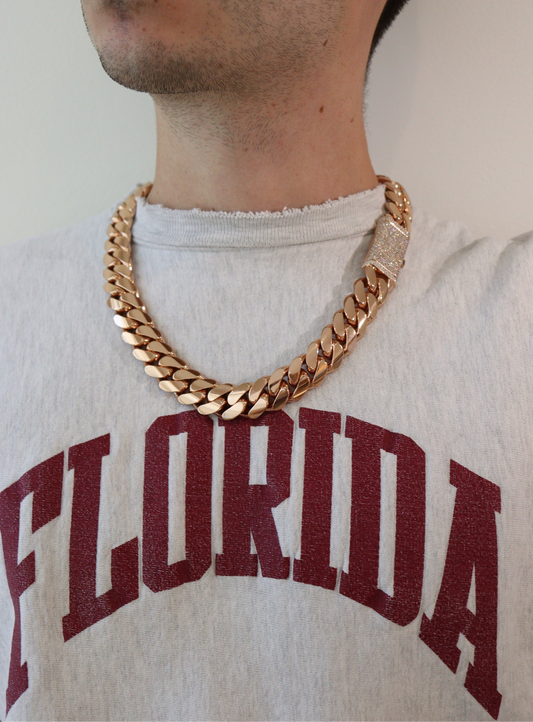 20MM Cuban Link Chain in rose gold over silver with fully iced-out VVS1 Moissanite Stones Lock, 24-inch length, modeled on a 6’1” 180 lbs male wearing a white shirt. Jewelry by SF Jeweler 305.