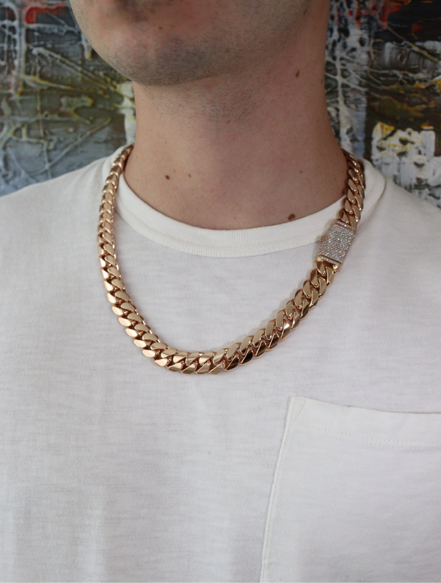 14MM Cuban Link Chain in rose gold over silver with fully iced-out VVS1 Moissanite Stones Lock, modeled on a 6’1” 180 lbs male wearing a white shirt. Jewelry by SF Jeweler 305.