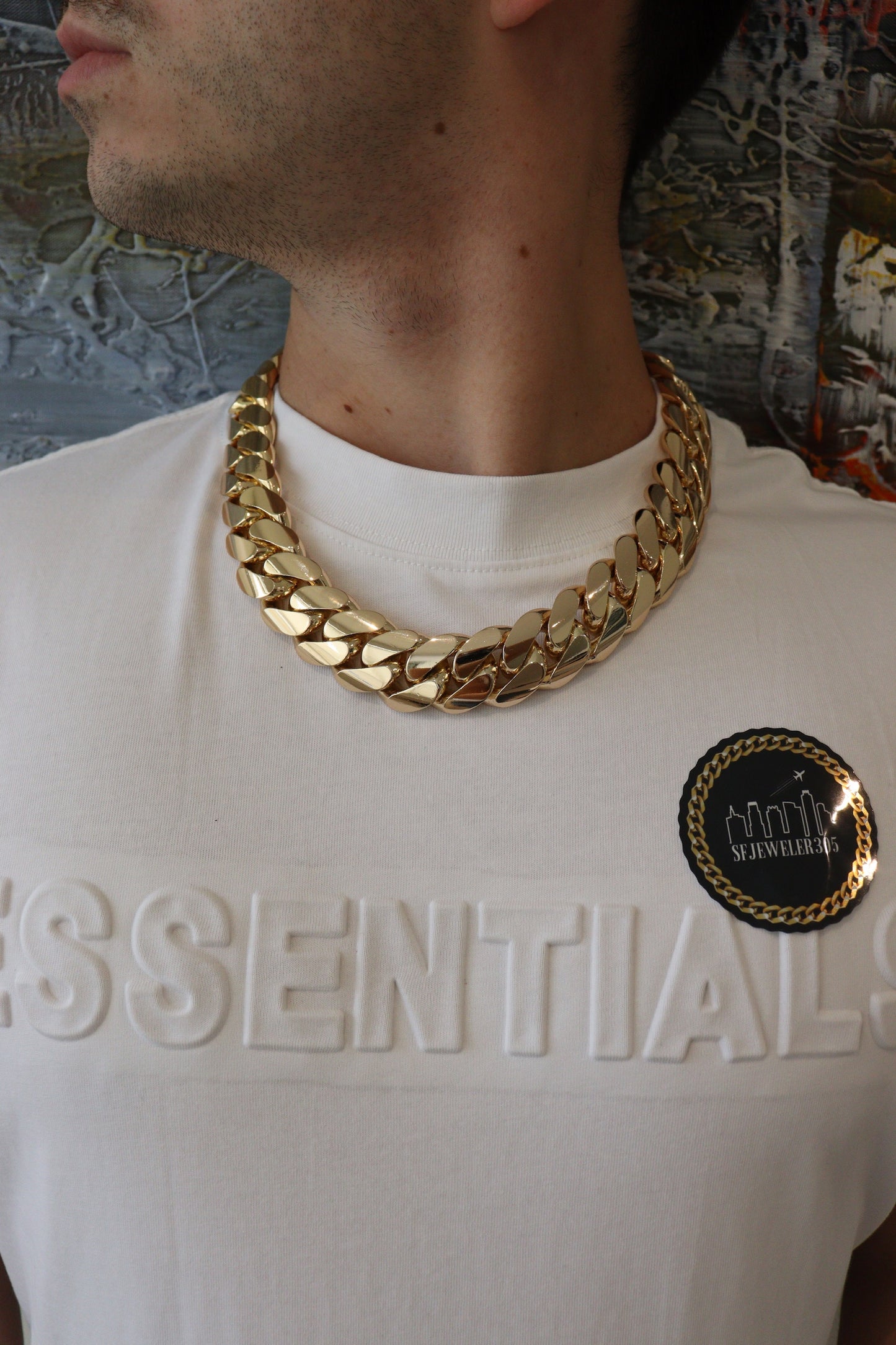 Man wearing a 24MM 22-inch Yellow gold over silver Cuban link chain, modeled by SF Jeweler 305. The bold Miami Cuban chain has a heavy, polished finish and is styled with a casual t-shirt.