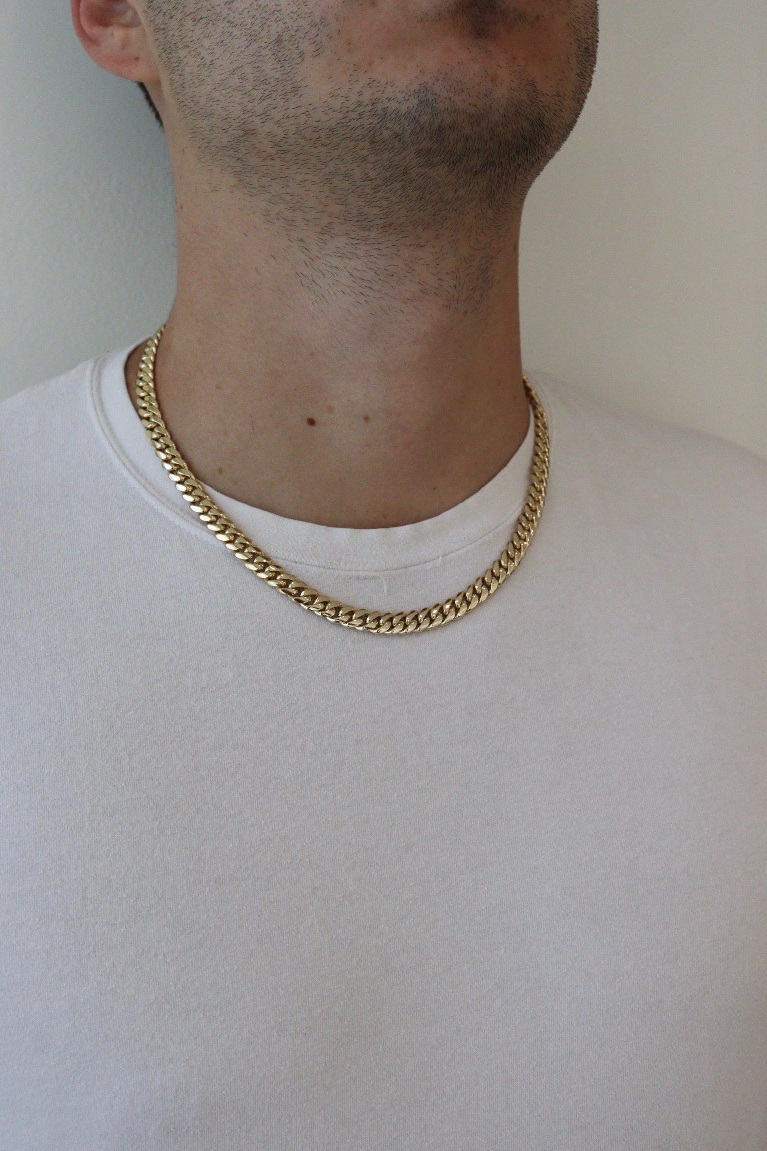 Man wearing a 8MM yellow gold over silver Cuban link chain, modeled by SF Jeweler 305. The bold Miami Cuban chain has a heavy, polished finish and is styled with a casual t-shirt.