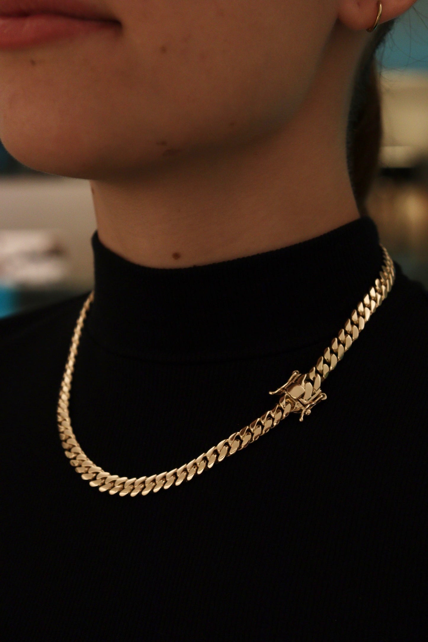 women wearing a 8MM yellow gold over silver Cuban link chain, modeled by SF Jeweler 305. The bold Miami Cuban chain has a heavy, polished finish and is styled with a casual t-shirt.