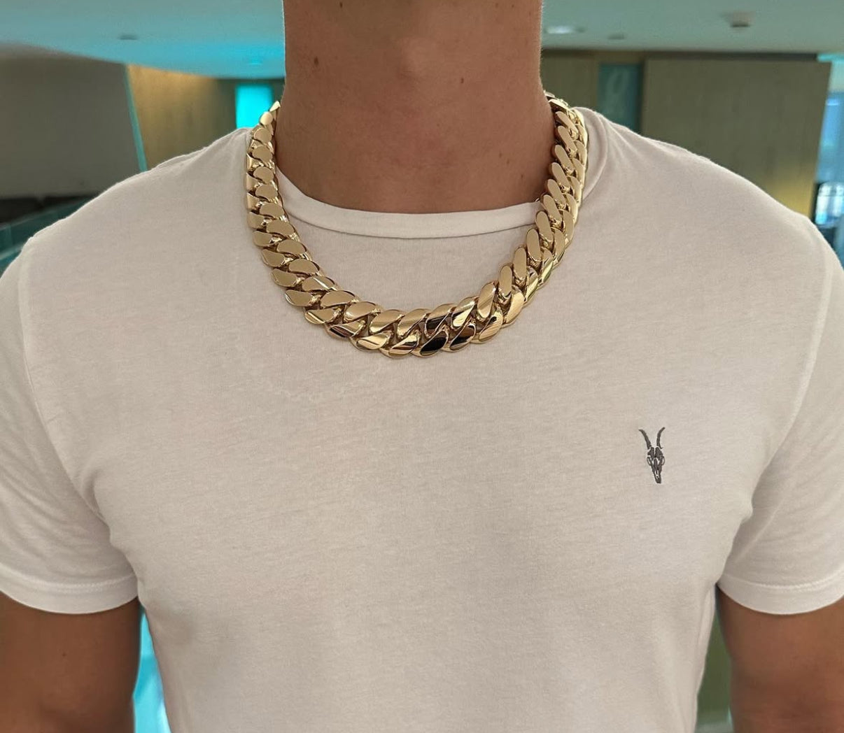 Man wearing a 22MM 22-inch yellow gold over silver Cuban link chain, modeled by SF Jeweler 305. The bold Miami Cuban chain has a heavy, polished finish and is styled with a casual t-shirt.