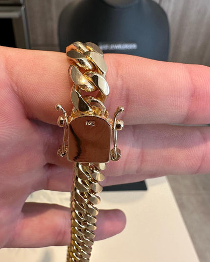 Man holding a 10MM  yellow gold over silver Cuban link chain, showing it stamped. The bold Miami Cuban chain has a heavy, polished finish and is styled with a casual t-shirt.