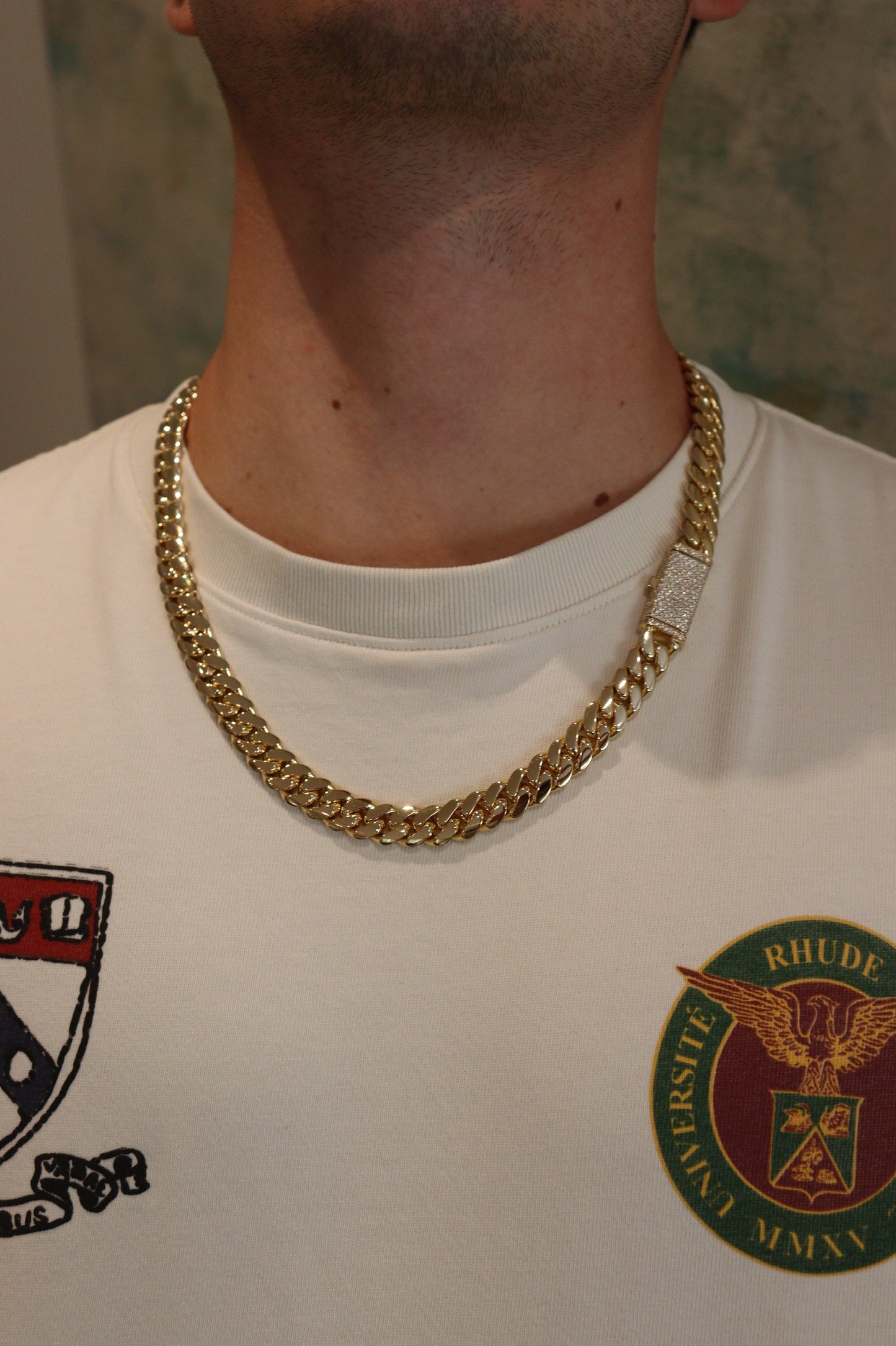12MM Cuban Link Chain in yellow gold with fully iced-out VVS1 Moissanite Stones Lock, modeled on a 6’1” 180 lbs male wearing a white shirt. Jewelry by SF Jeweler 305.