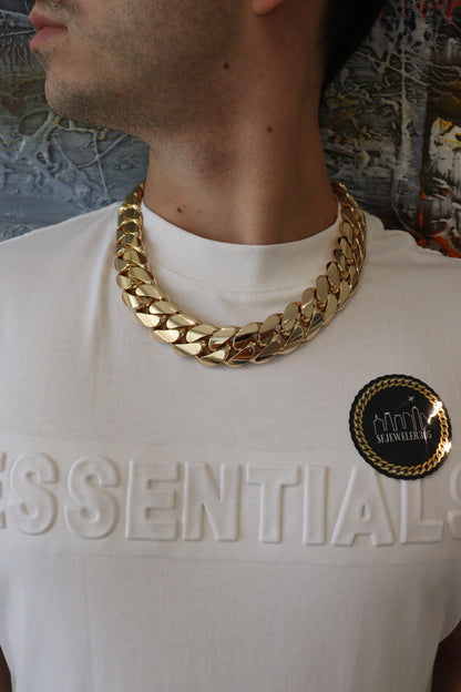 Man wearing a 24MM 22-inch Yellow gold over silver Cuban link chain, modeled by SF Jeweler 305. The bold Miami Cuban chain has a heavy, polished finish and is styled with a casual t-shirt.