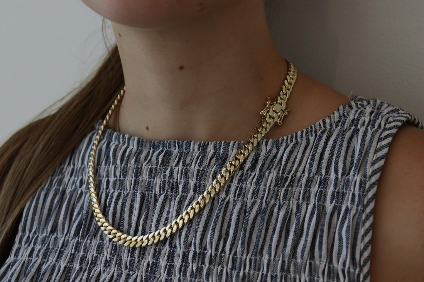 women wearing a 8MM yellow gold over silver Cuban link chain, modeled by SF Jeweler 305. The bold Miami Cuban chain has a heavy, polished finish and is styled with a casual t-shirt.