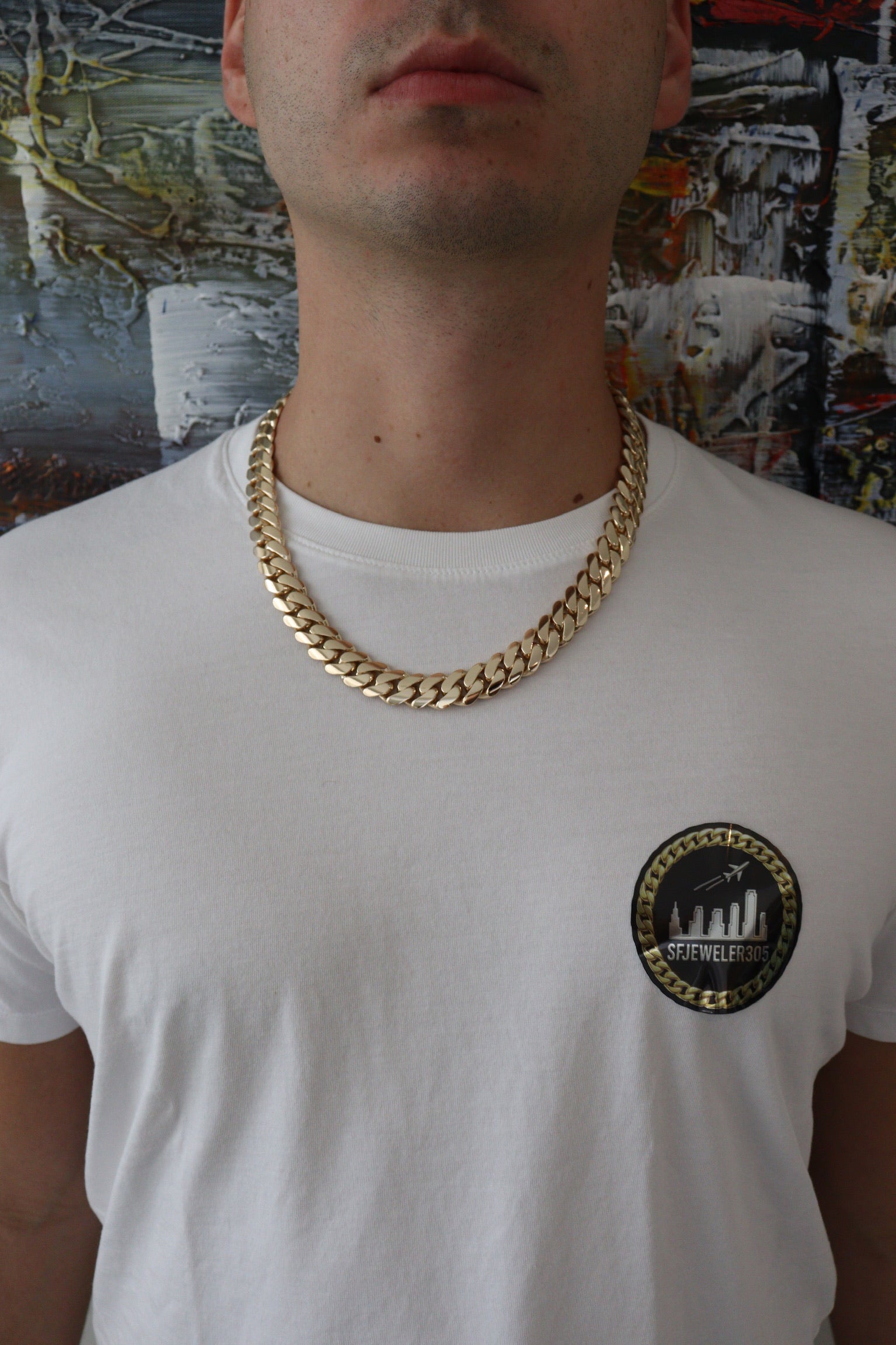 Man wearing a 14MM yellow gold over silver Cuban link chain, modeled by SF Jeweler 305. The bold Miami Cuban chain has a heavy, polished finish and is styled with a casual t-shirt.