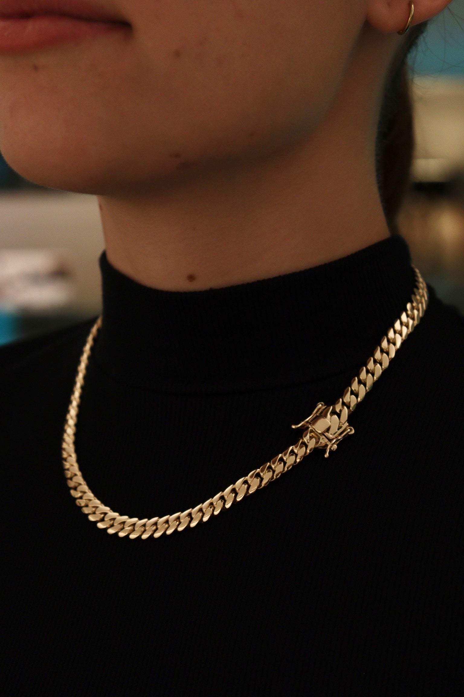 women wearing a 8MM yellow gold over silver Cuban link chain, modeled by SF Jeweler 305. The bold Miami Cuban chain has a heavy, polished finish and is styled with a casual t-shirt.
