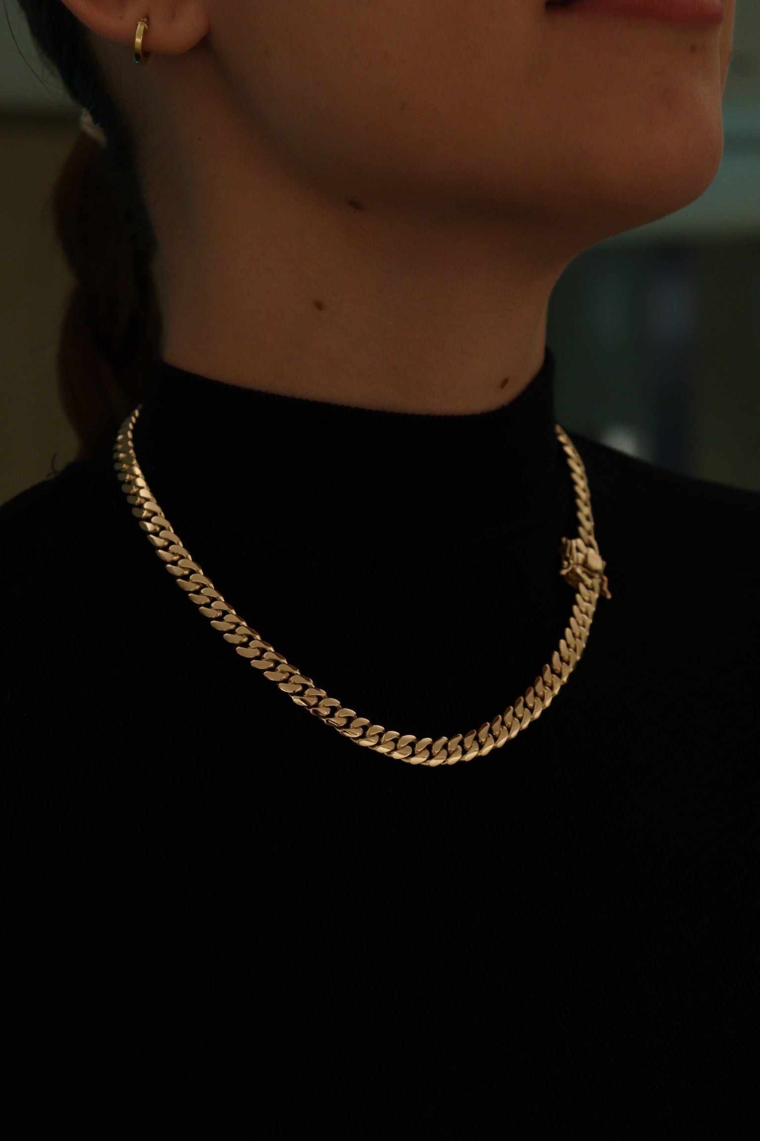 women wearing a 8MM yellow gold over silver Cuban link chain, modeled by SF Jeweler 305. The bold Miami Cuban chain has a heavy, polished finish and is styled with a casual t-shirt.
