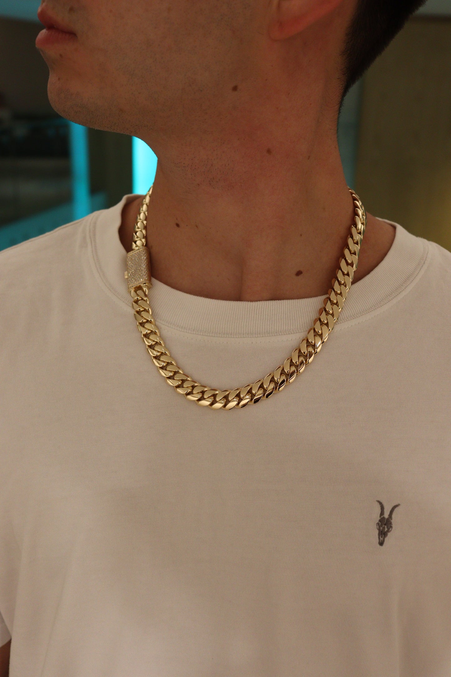 12MM Cuban Link Chain in yellow gold with fully iced-out VVS1 Moissanite Stones Lock, modeled on a 6’1” 180 lbs male wearing a white shirt. Jewelry by SF Jeweler 305.