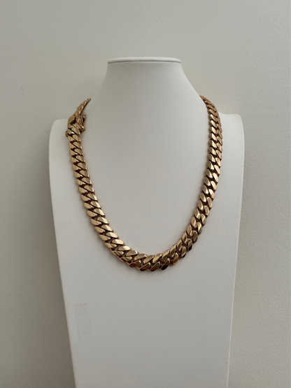 Man wearing a 14MM yellow gold over silver Cuban link chain, modeled by SF Jeweler 305. The bold Miami Cuban chain has a heavy, polished finish and is styled with a casual t-shirt.