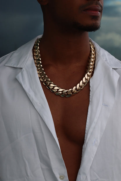 Man wearing a 20MM 24-inch yellow gold over silver Cuban link chain, modeled by SF Jeweler 305. The bold Miami Cuban chain has a heavy, polished finish and is styled with a casual t-shirt.