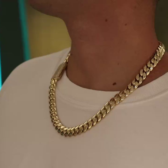 12MM Cuban Link Chain in yellow gold with fully iced-out VVS1 Moissanite Stones Lock, 24-inch length, modeled on a 6’1” 180 lbs male wearing a white shirt. Jewelry by SF Jeweler 305.